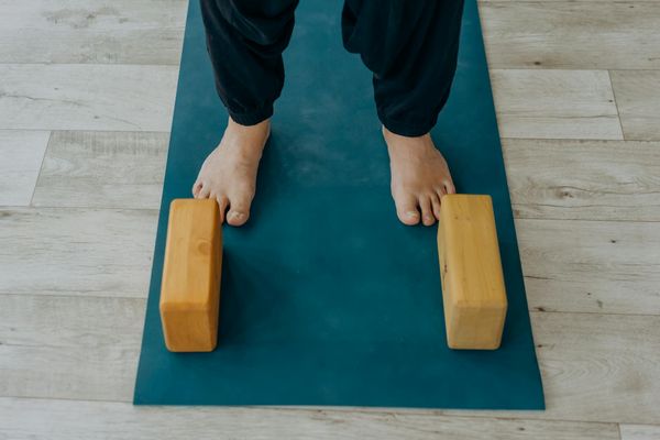 Wooden yoga block and a mat in a sunny room.