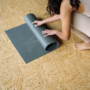 Yoga mat rolled up on a clean wooden floor.